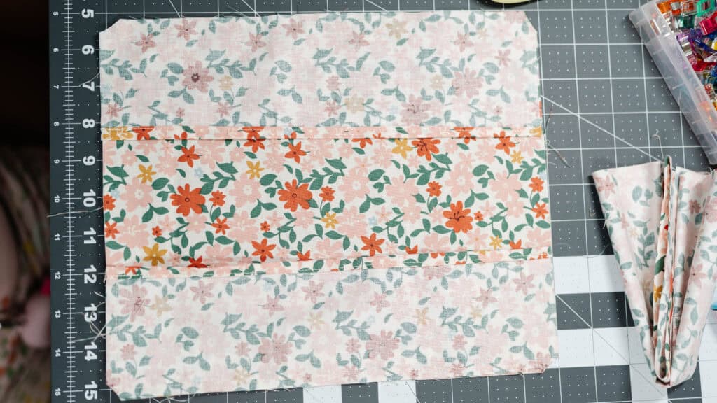 Happy Stitches sewing project supplies for a Crayon Wrap Roll, including fabric pieces, Clover Hot Ruler, Rotary Cutter, Heart-Shaped Pins, Wonder Clips, and Roll & Press