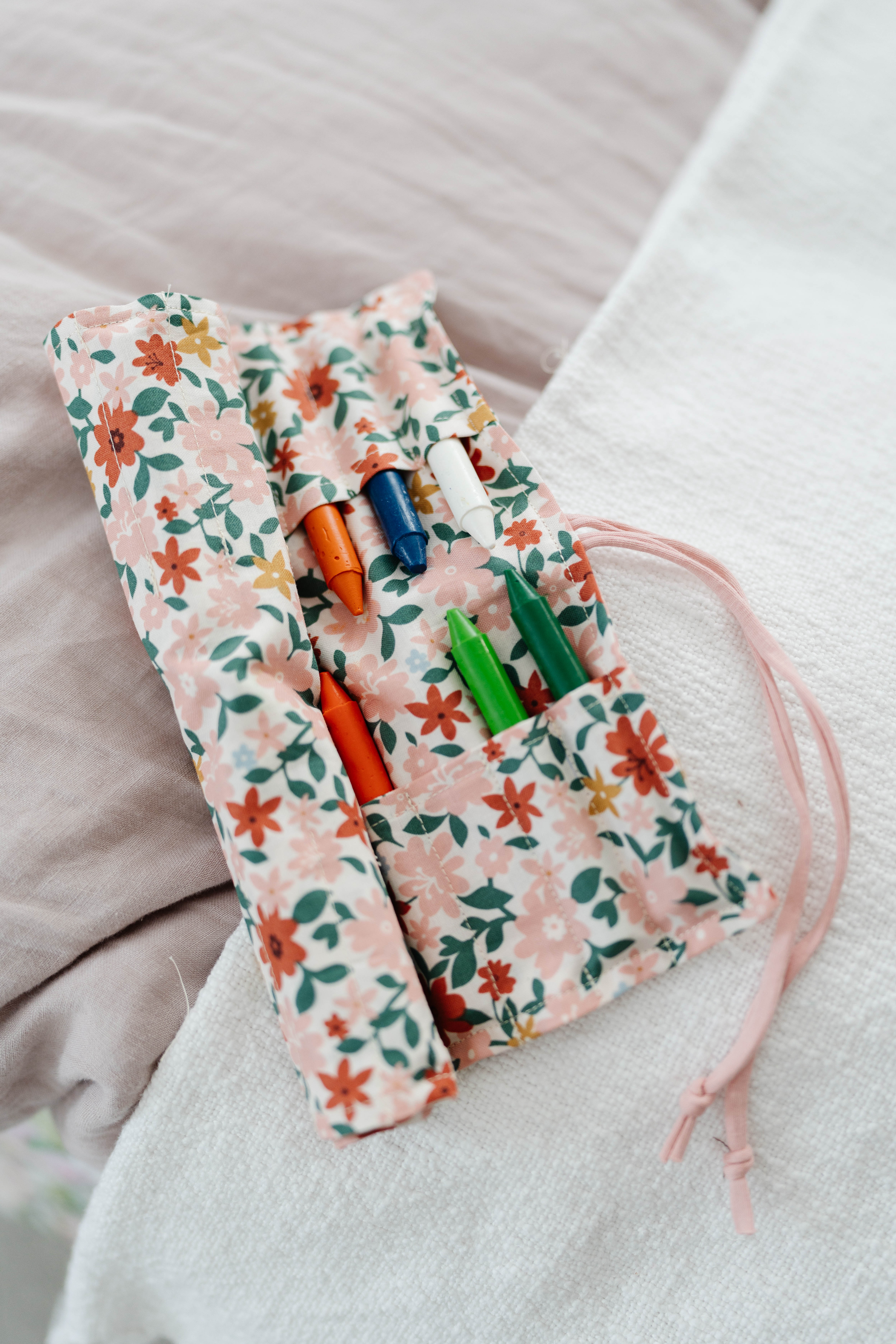 Happy Stitches sewing project supplies for a Crayon Wrap Roll, including fabric pieces, Clover Hot Ruler, Rotary Cutter, Heart-Shaped Pins, Wonder Clips, and Roll & Press